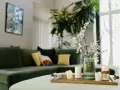 Zielona kanapa, świece i kwiaty na tacy tworzą harmonię w stylu feng shui.