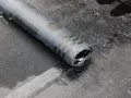 Zrolowana papa na zimno, z widocznymi czarnymi wzorami, leży na mokrej, szarej powierzchni.