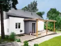 Drewniany taras z pergolą to świetny pomysł na taras przed domem. Urocze meble z palet i biały stolik zapraszają do relaksu.