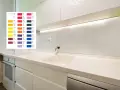 Próbnik kolorów płyty laminowanej nad blatem kuchennym, obok białych szafek.