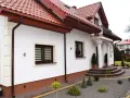 Elegancki cokół na elewacji domu, podkreślony brązowym tynkiem, harmonizuje z dachówką i stolarką okienną.