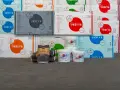 Stosy opakowań styropianu i wiader z produktami budowlanymi, w tym klej do styropianu Justyr.