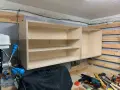 Solidne mocowanie szafek wiszących do ściany za pomocą drewnianych wsporników. Widać narzędzia i materiały do majsterkowania.