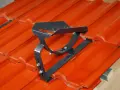 Metalowe stopnie kominiarskie zamontowane na pomarańczowej dachówce. Zapewniają bezpieczeństwo podczas prac na dachu.