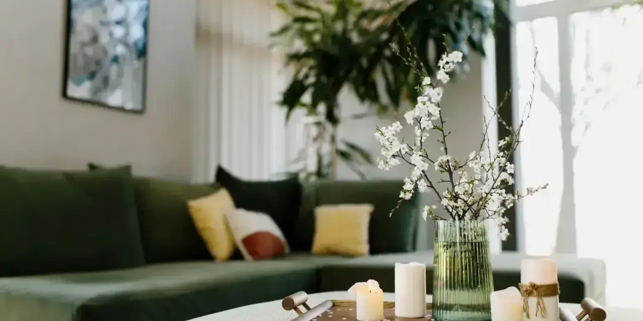 Zielona kanapa, świece i kwiaty na tacy tworzą harmonię w stylu feng shui.