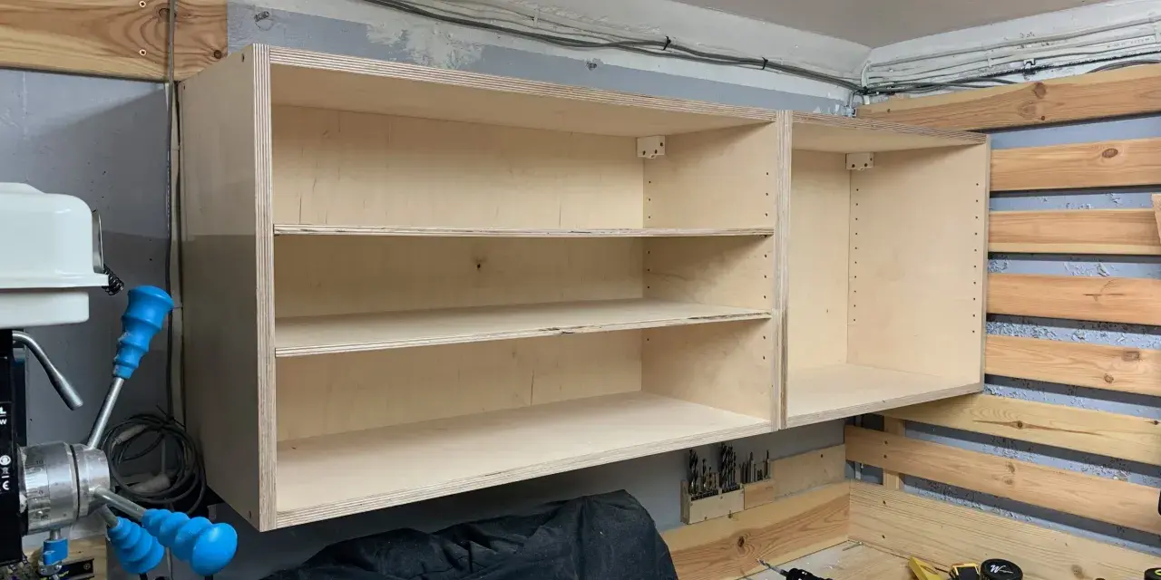Solidne mocowanie szafek wiszących do ściany za pomocą drewnianych wsporników. Widać narzędzia i materiały do majsterkowania.