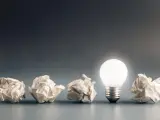 Zepsute pomysły, jak zużyte żarówki, gdzie wyrzucić? Jedna świeci jasno, symbolizując nową ideę.