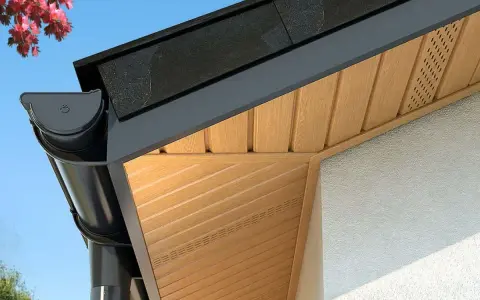 Drewniana podbitka dachu z systemem rynnowym i fragmentem elewacji.