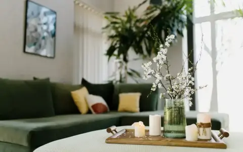 Zielona kanapa, świece i kwiaty na tacy tworzą harmonię w stylu feng shui.