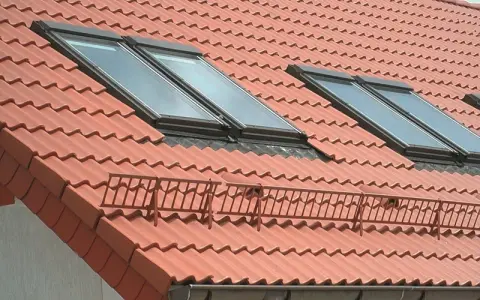 Nowy dach z dachówką ceramiczną, orynnowanie i okna dachowe zapewniające światło.