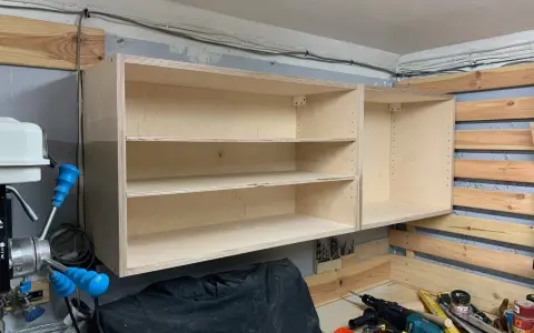 Solidne mocowanie szafek wiszących do ściany za pomocą drewnianych wsporników. Widać narzędzia i materiały do majsterkowania.