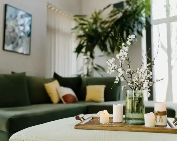 Zielona kanapa, świece i kwiaty na tacy tworzą harmonię w stylu feng shui.