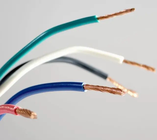 Kilka kolorowych przewodów elektrycznych, w tym niebieski, zielony, biały, czarny i różowy, z odsłoniętymi miedzianymi żyłami.