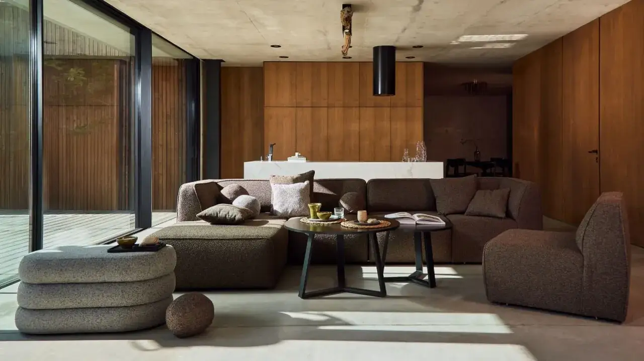 Nowoczesny salon w stylu bauhaus z wygodną sofą, stolikami i dużą ilością drewna.