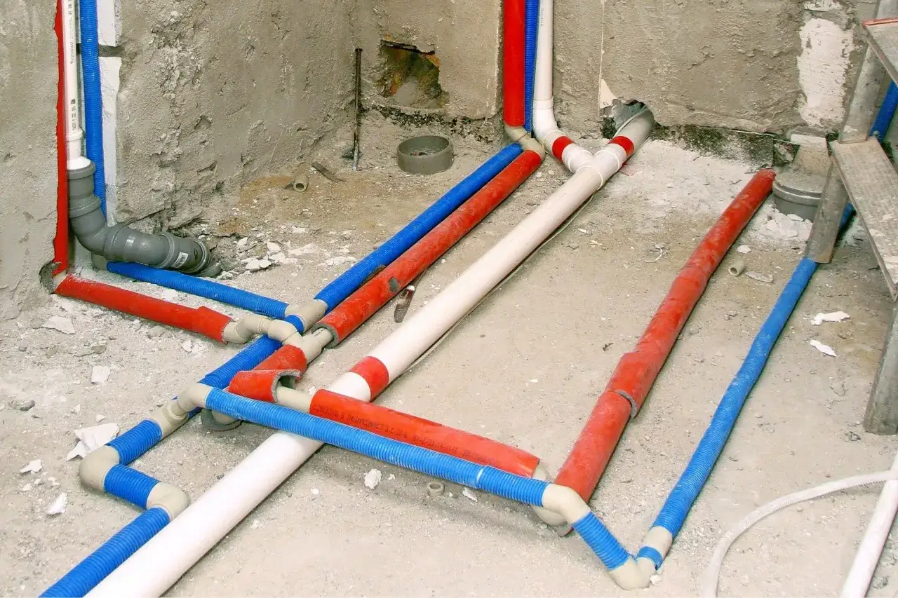 Skomplikowana instalacja wodna z rurami PP w kolorach czerwonym, niebieskim i białym, przygotowana do tynkowania.