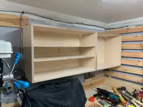 Solidne mocowanie szafek wiszących do ściany za pomocą drewnianych wsporników. Widać narzędzia i materiały do majsterkowania.
